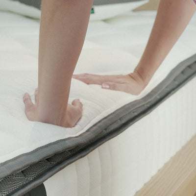 A woman evaluates the firmness of a Valmori Firm Spring Mattress