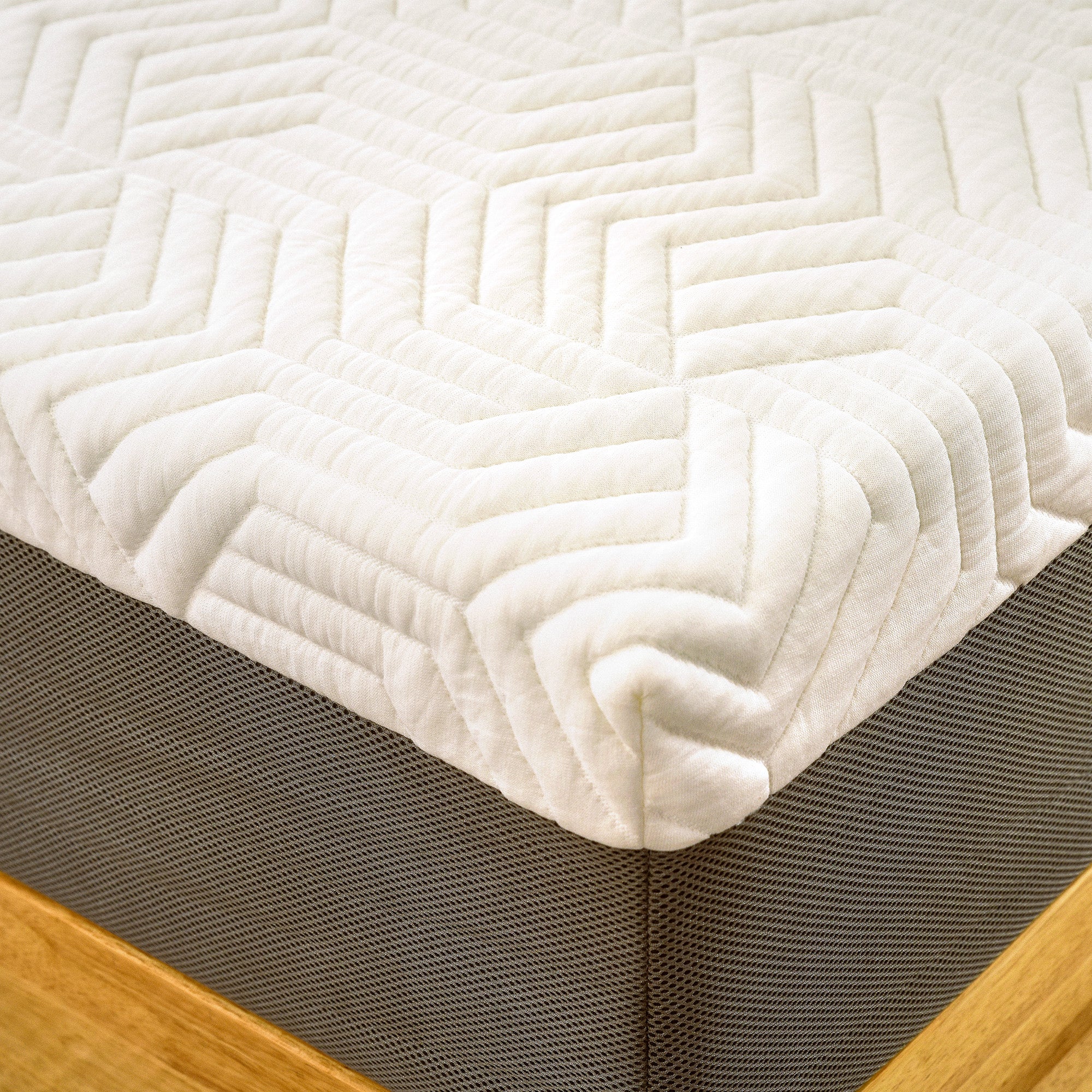 A close-up of the corner of a Valmori Hybrid Mattress Ⅱ (Medium) with a white, textured cover featuring a geometric pattern.