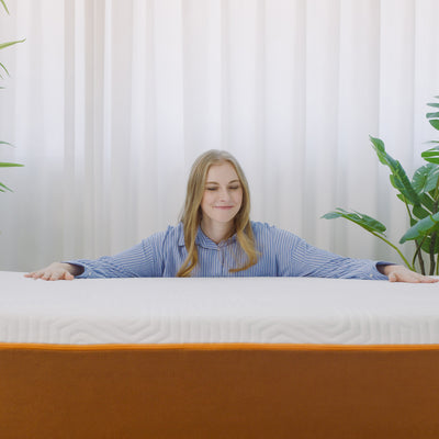 A person in a blue striped shirt sitting behind a Valmori S-Shape Medium Foam Mattress