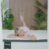 A blonde woman smiles warmly as she lounges atop a Valmori Spring Mattress Firm