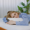 A woman lying on a Valmori Medium S-Shape Foam Mattress Ⅱ bed, and resting their head on a valmori pillow.