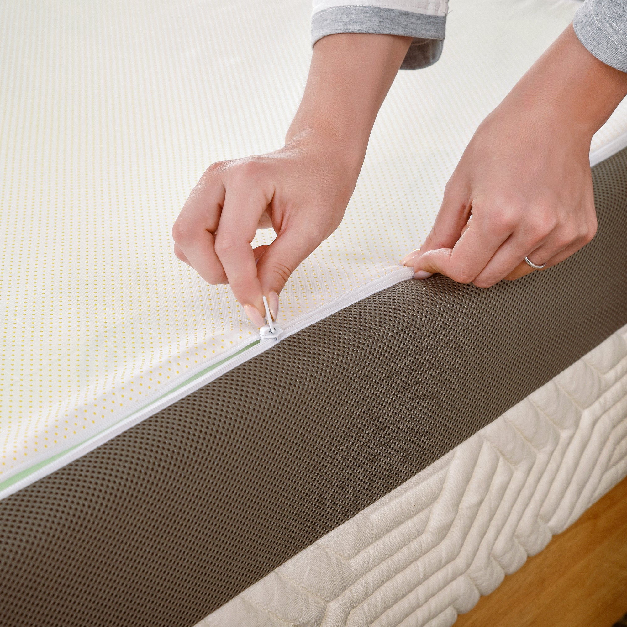 A person zipping up a Valmori Hybrid Mattress Ⅱ (Medium) mattress cover.